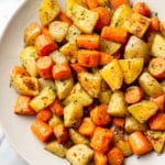 roasted potatoes and carrots in a white serving bowl