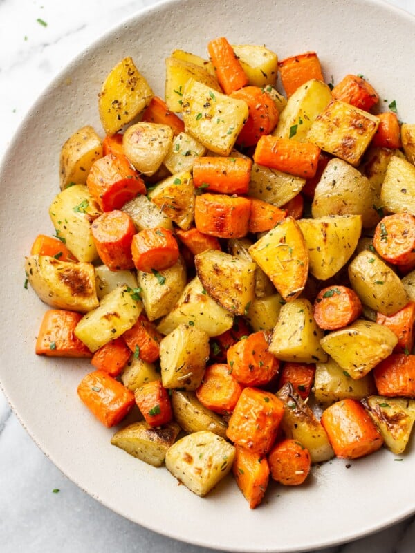 roasted potatoes and carrots in a white serving bowl