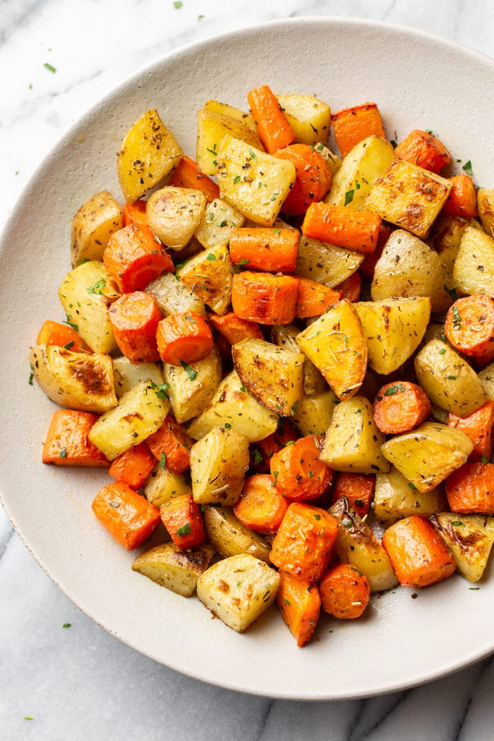 roasted potatoes and carrots in a white serving bowl