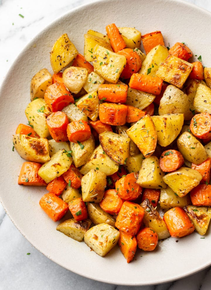 roasted potatoes and carrots in a white serving bowl