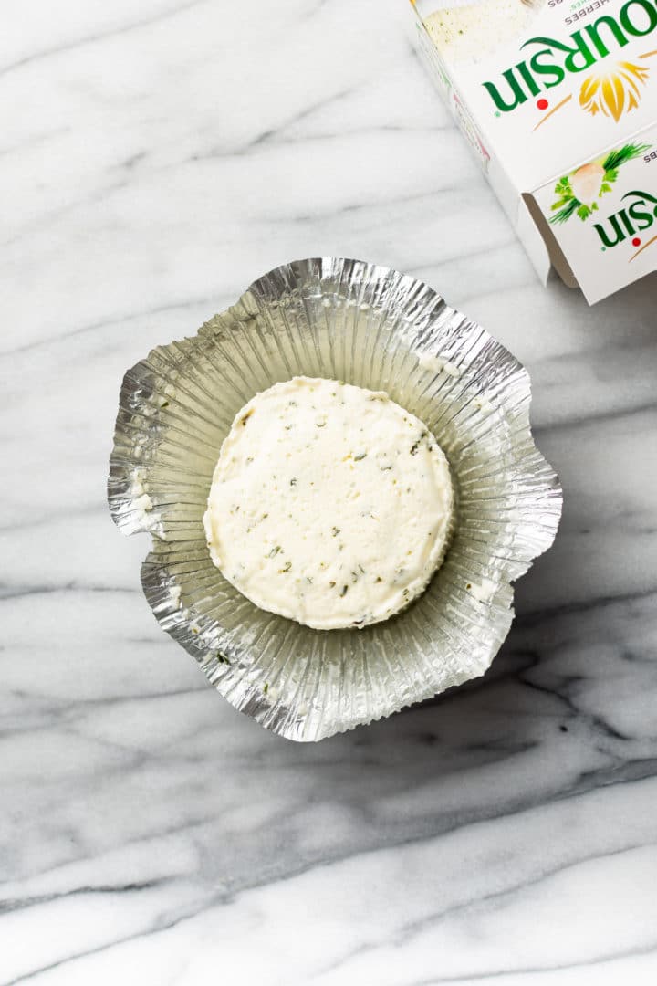 Boursin cheese sitting in open foil wrapper with its packaging box to the side