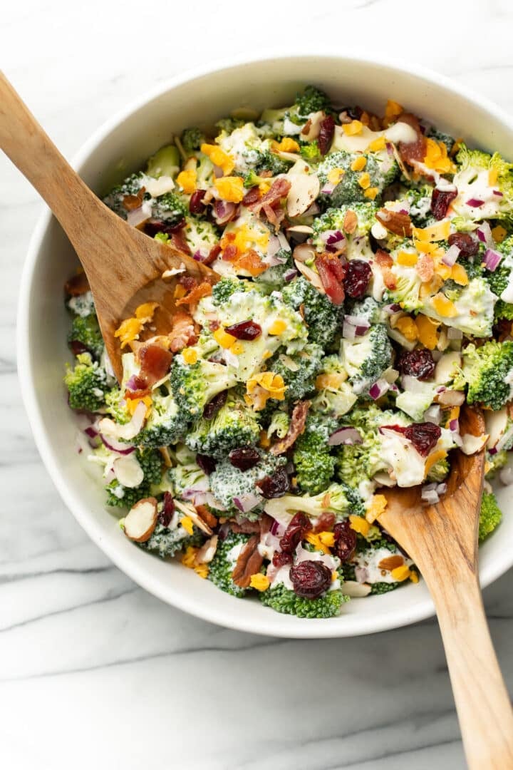 a bowl of broccoli salad with serving utensils