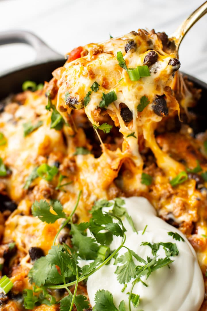 cheesy beef taco skillet close-up with a spoonful being lifted out of the pan