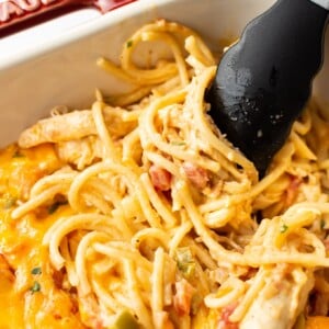 close-up of easy chicken spaghetti being lifted by tongs in a casserole dish