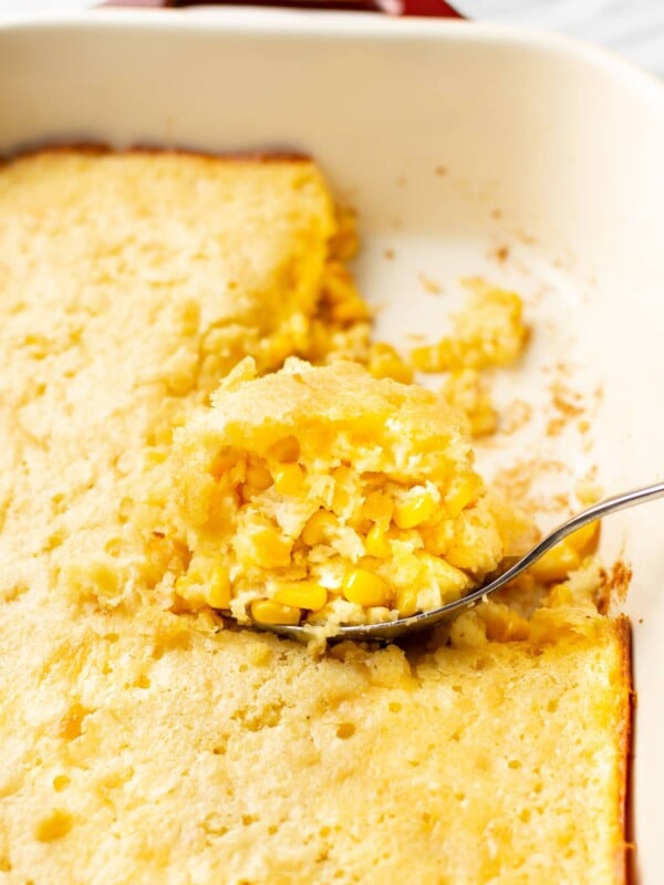 Jiffy corn casserole close-up with a portion being lifted out of the baking dish