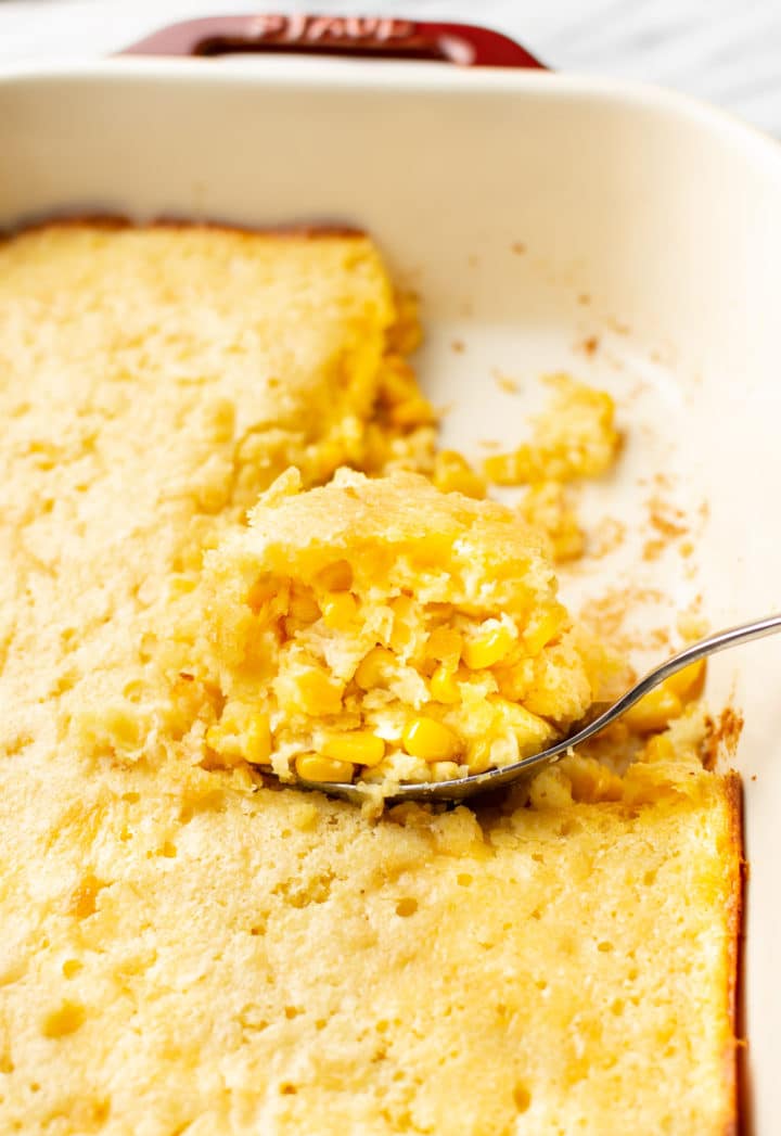 Jiffy corn casserole close-up with a portion being lifted out of the baking dish