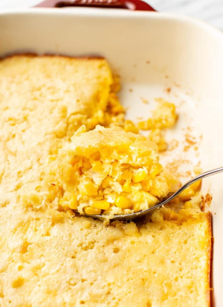 Jiffy corn casserole close-up with a portion being lifted out of the baking dish