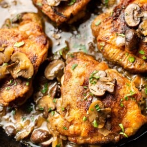 white wine chicken thighs with mushroom herb butter sauce in a skillet close-up