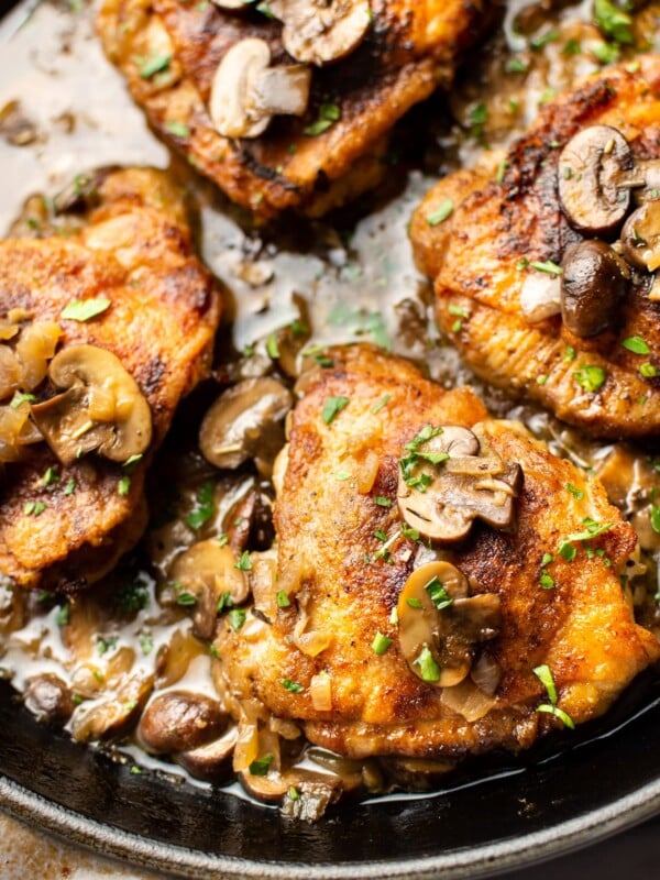 white wine chicken thighs with mushroom herb butter sauce in a skillet close-up