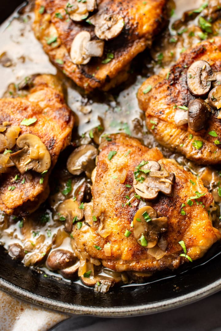 white wine chicken thighs with mushroom herb butter sauce in a skillet close-up