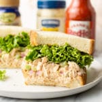 buffalo chicken sandwich cut in half surrounded by Frank's Red hot sauce, blue cheese dressing, and a jar of Hellmann's mayo