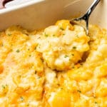 close-up of cheesy potato casserole with a large spoonful being lifted out