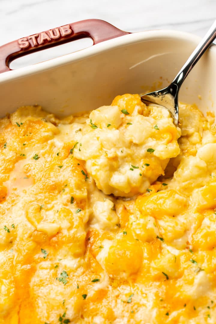 close-up of cheesy potato casserole with a large spoonful being lifted out