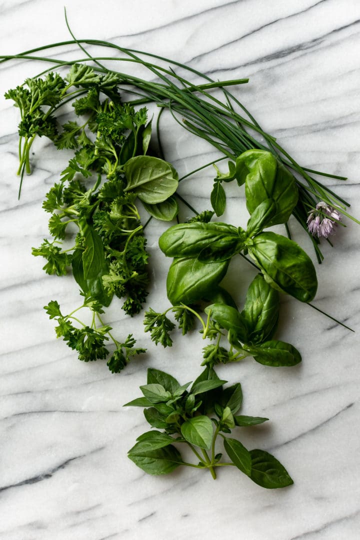 fresh basil, parsley, and chives on a marble background