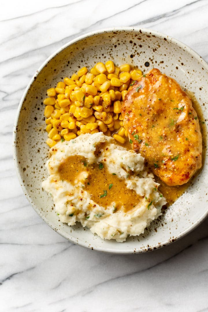 honey mustard chicken in a shallow bowl with mashed potatoes and sweet corn