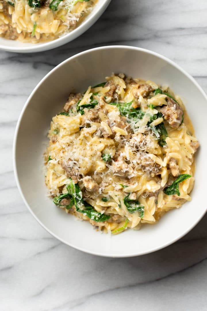 creamy Italian sausage orzo in two white bowls