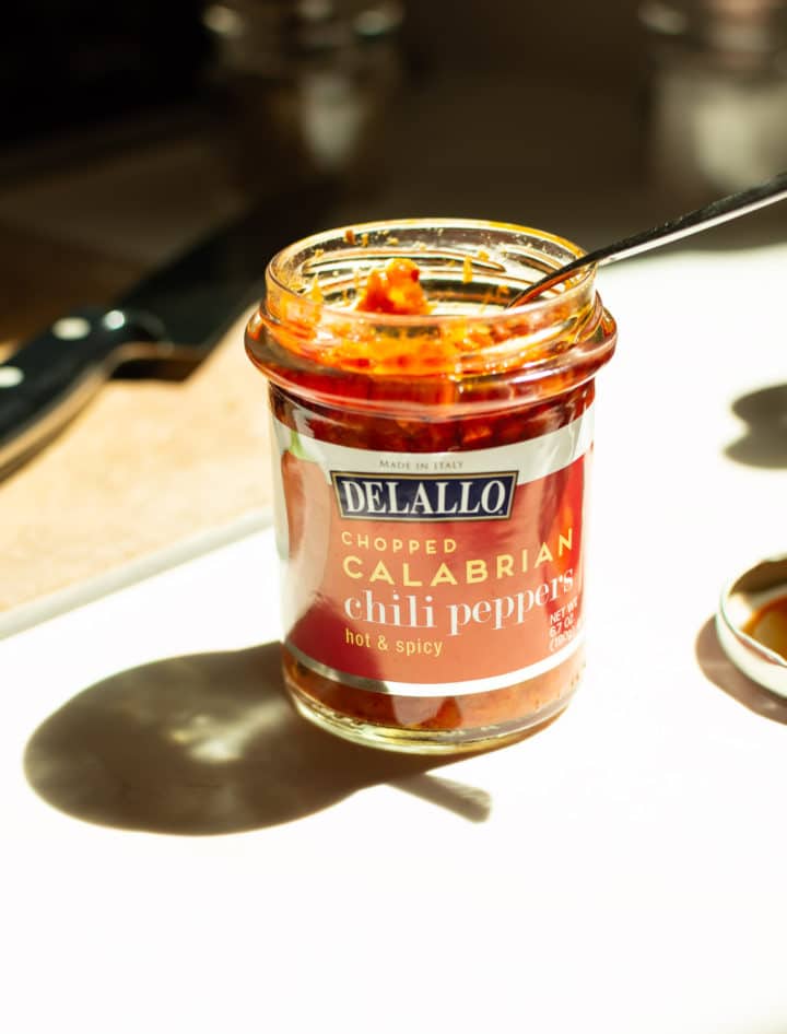 DeLallo Chopped Calabrian Chili Peppers in a jar with a spoon inside