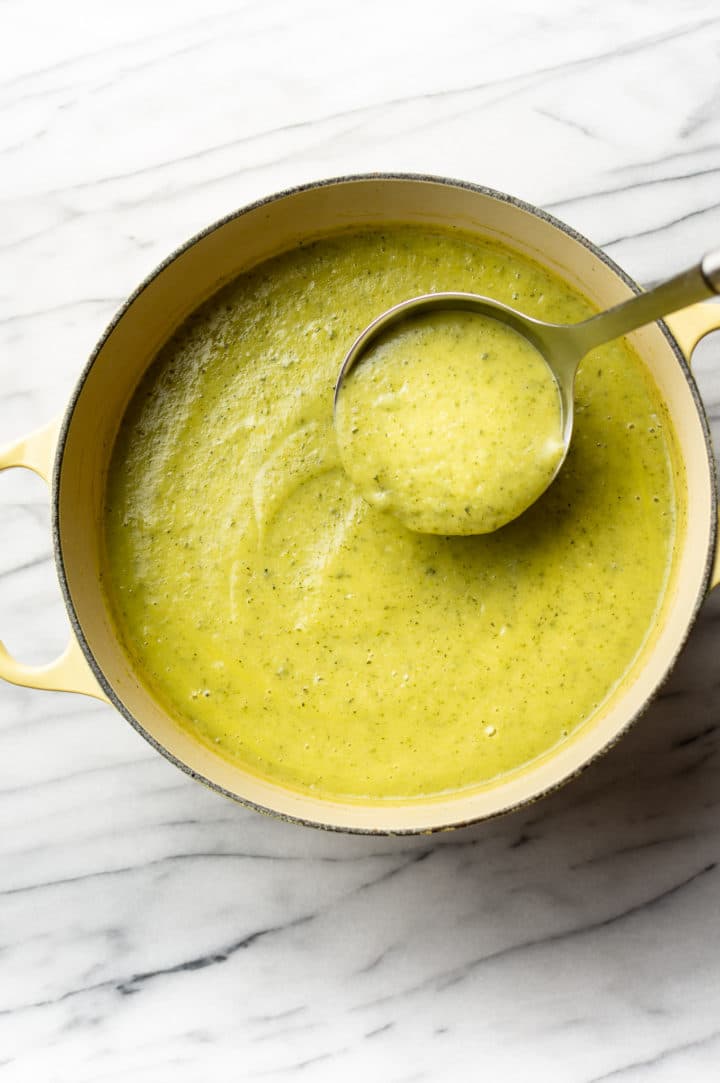 zucchini soup in a yellow pot with a ladle