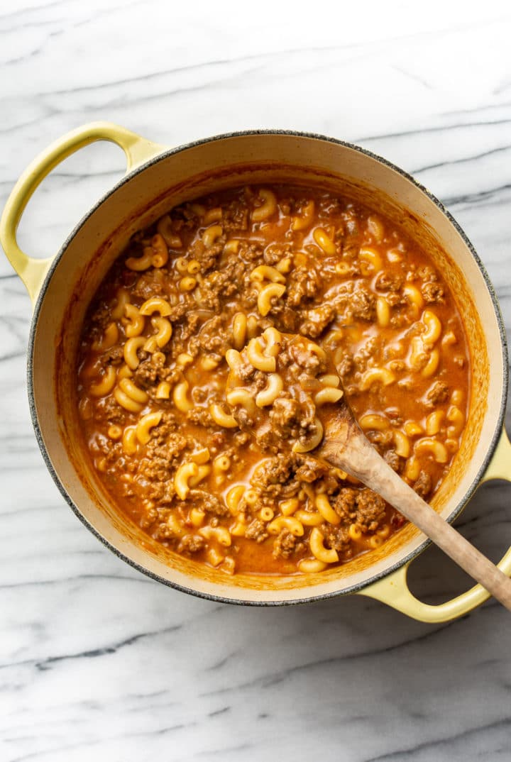 cheeseburger macaroni in a Dutch oven with a wooden spoon
