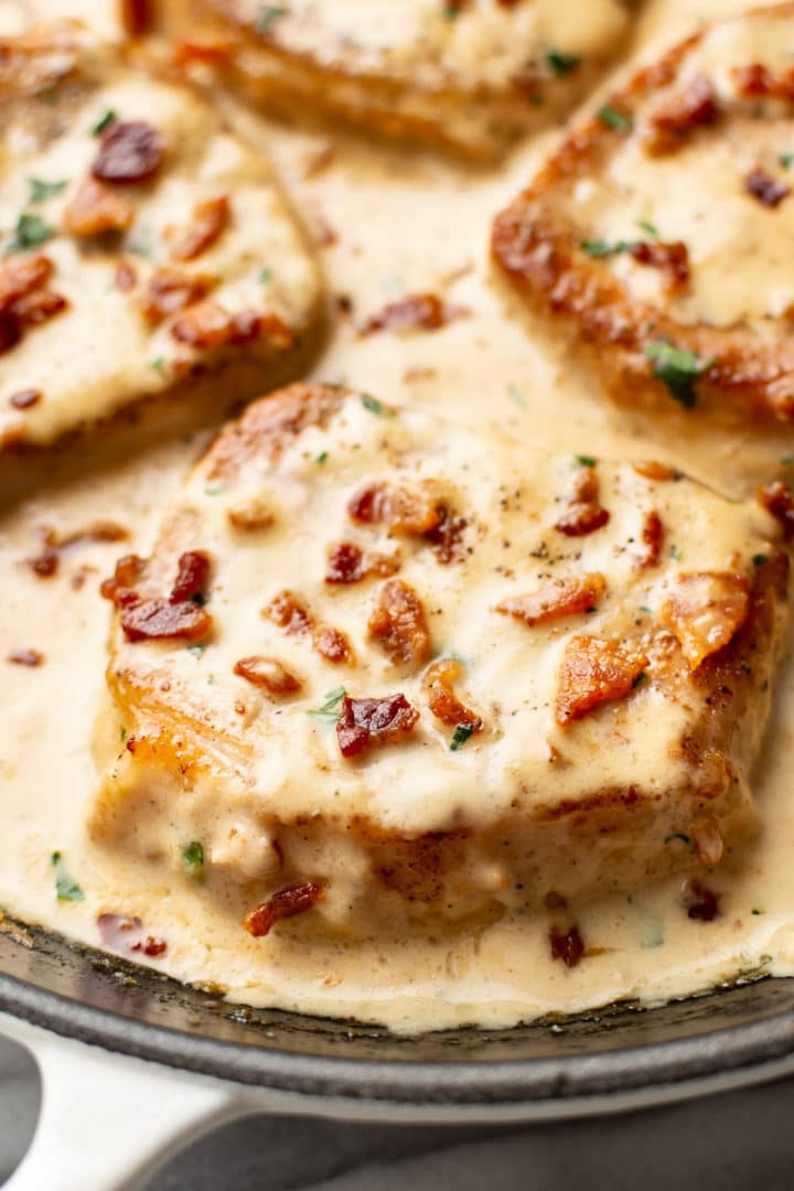 close-up of creamy bacon pork chops in a skillet