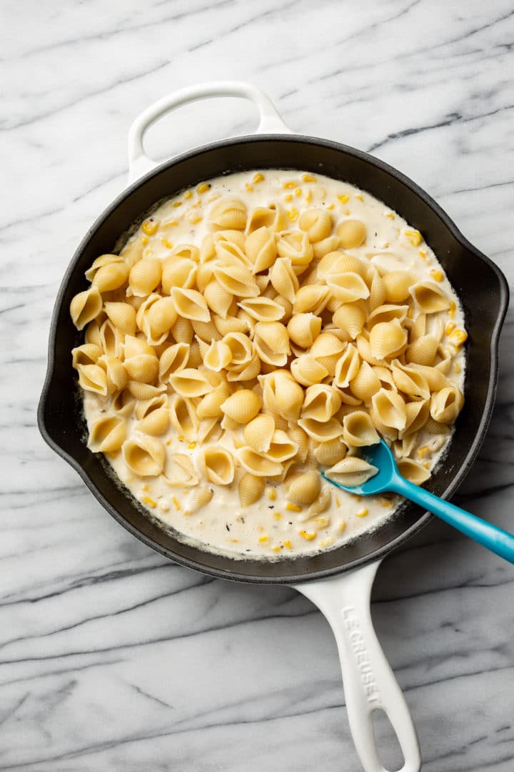 creamed corn pasta sauce ready to be tossed with shell pasta in a white skillet