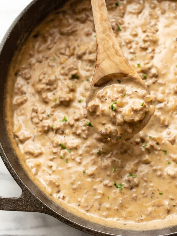 closeup of a skillet of hamburger gravy with a serving spoon