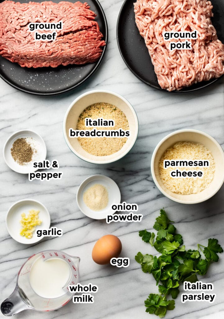 ingredients for meatballs in bowls on a marble surface
