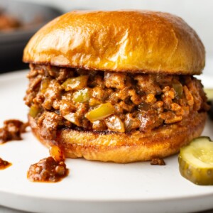 close-up of homemade Sloppy Joe sandwich on a white plate with pickles