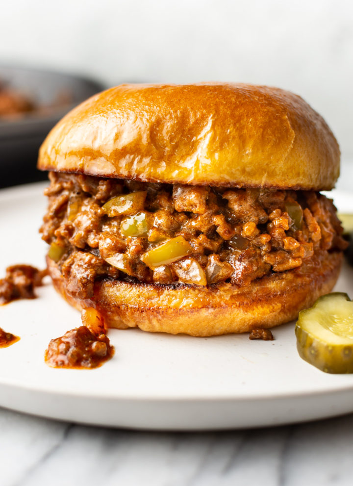close-up of homemade Sloppy Joe sandwich on a white plate with pickles