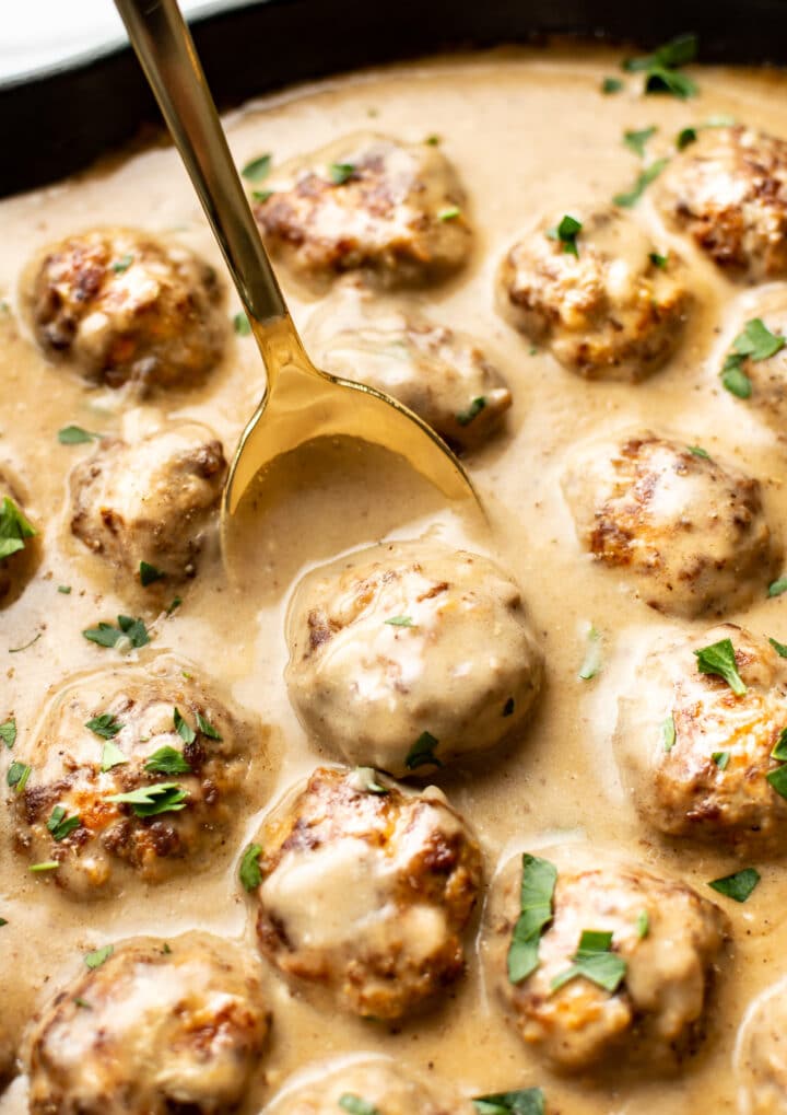 close-up of a spoon with a swedish meatballs over a skillet