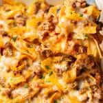 close-up of a spatula lifting a portion of beef and noodle casserole out of a baking dish