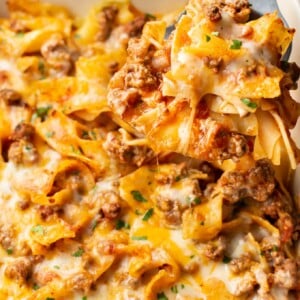 close-up of a spatula lifting a portion of beef and noodle casserole out of a baking dish