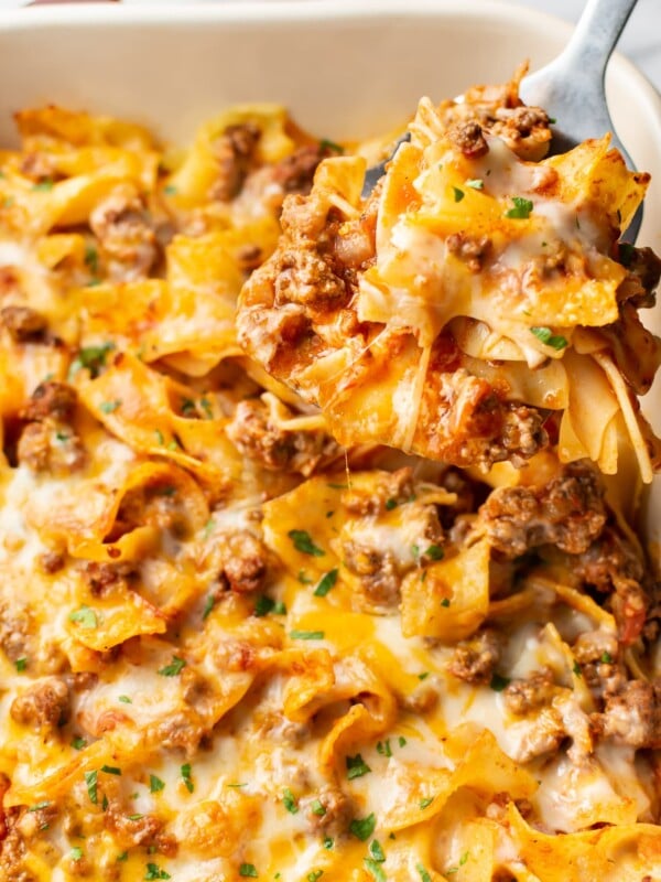 close-up of a spatula lifting a portion of beef and noodle casserole out of a baking dish