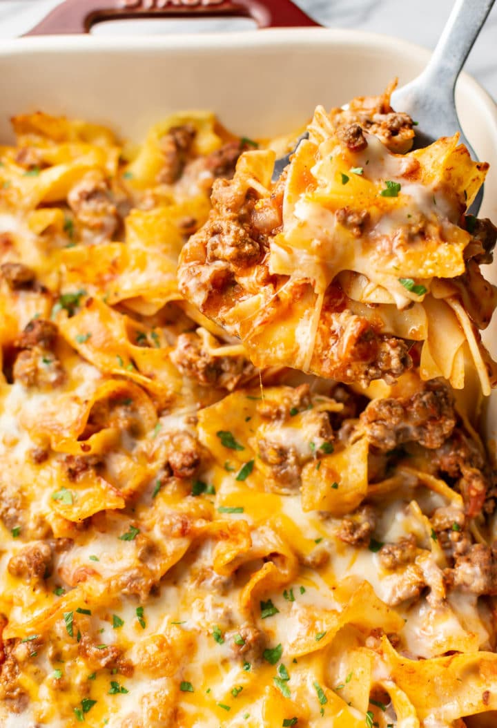 close-up of a spatula lifting a portion of beef and noodle casserole out of a baking dish