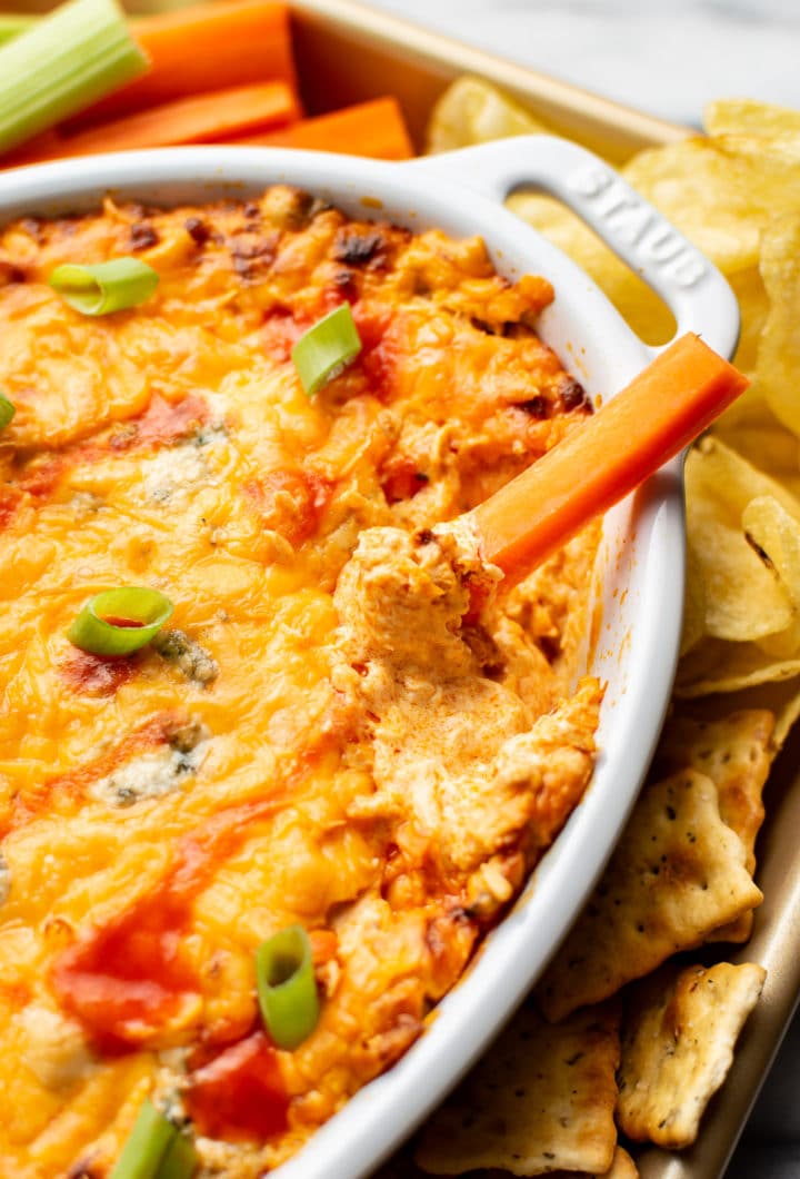 a carrot being dipped into easy buffalo chicken dip