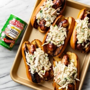 Cajun beer brats on a golden tray with Tony Chachere's Original Creole Seasoning beside it