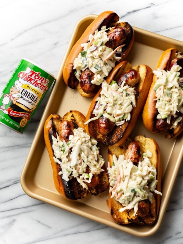 Cajun beer brats on a golden tray with Tony Chachere's Original Creole Seasoning beside it