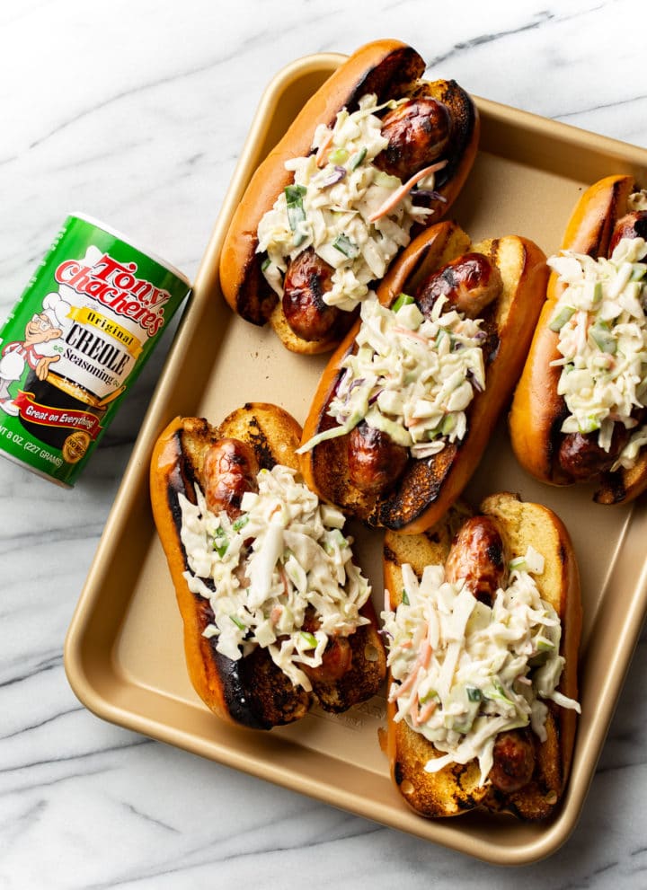 Cajun beer brats on a golden tray with Tony Chachere's Original Creole Seasoning beside it