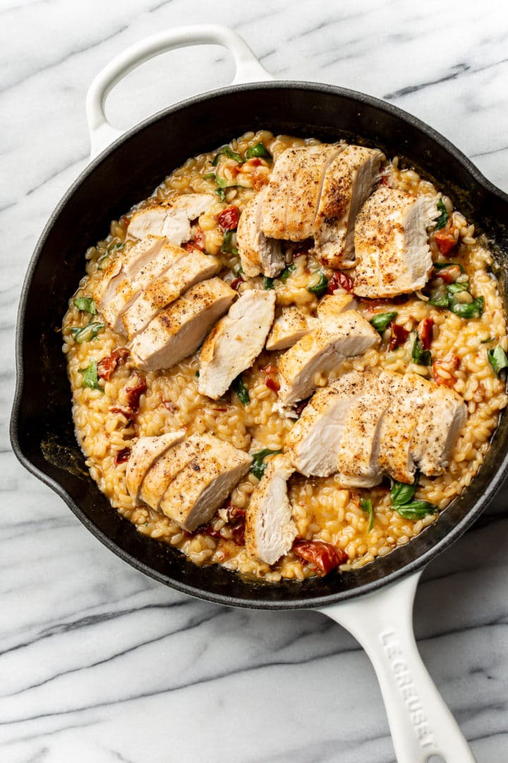 close-up of easy risotto with chicken, sun-dried tomatoes, and basil in a skillet