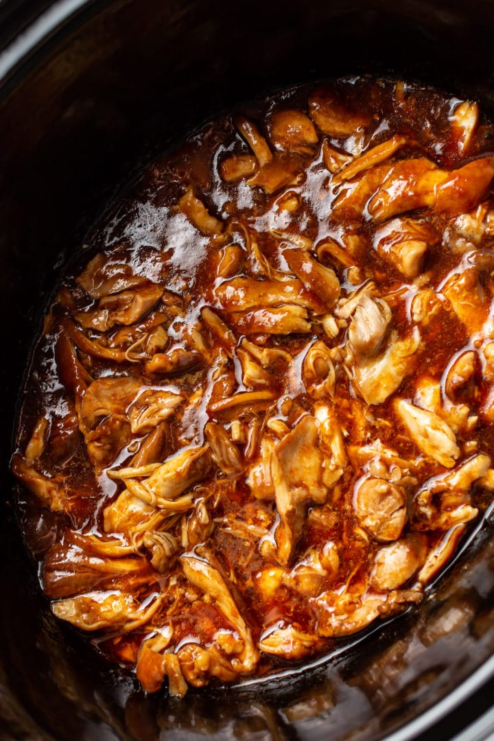 close-up of honey garlic slow cooker chicken thighs shredded in Crockpot