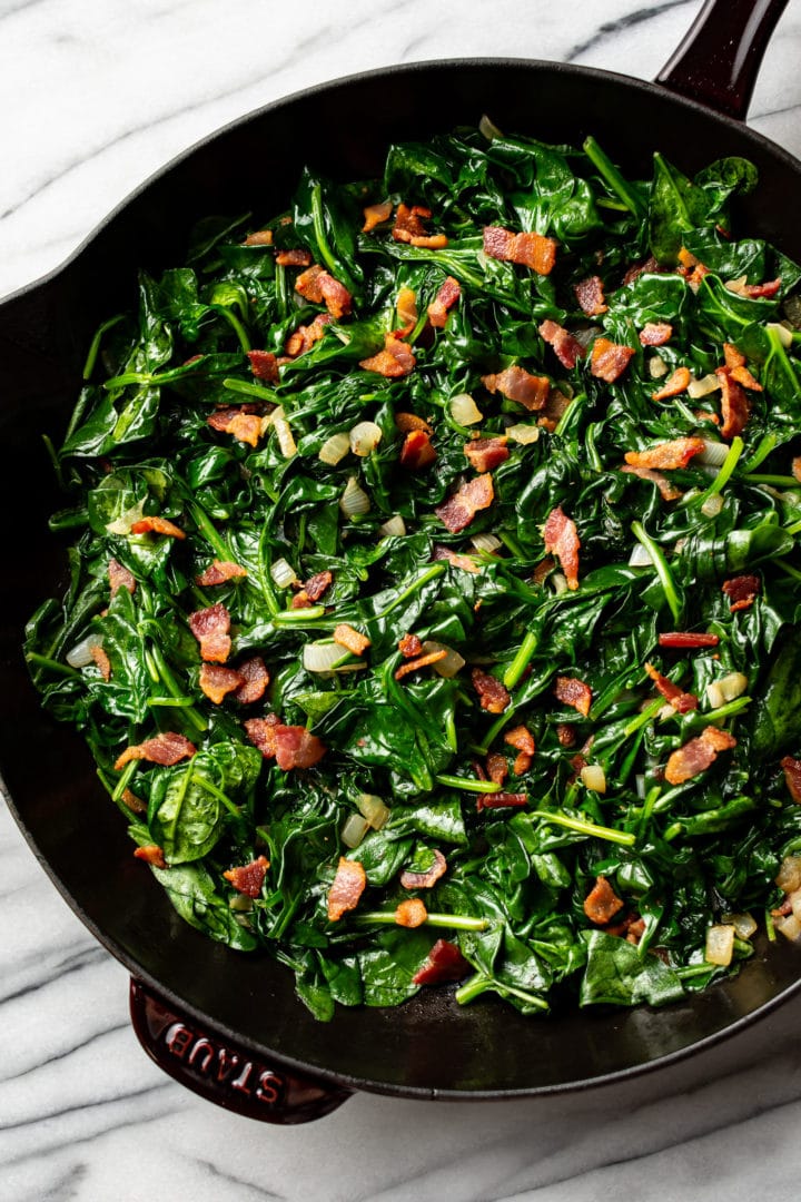 sauteed spinach with bacon in a cast iron skillet