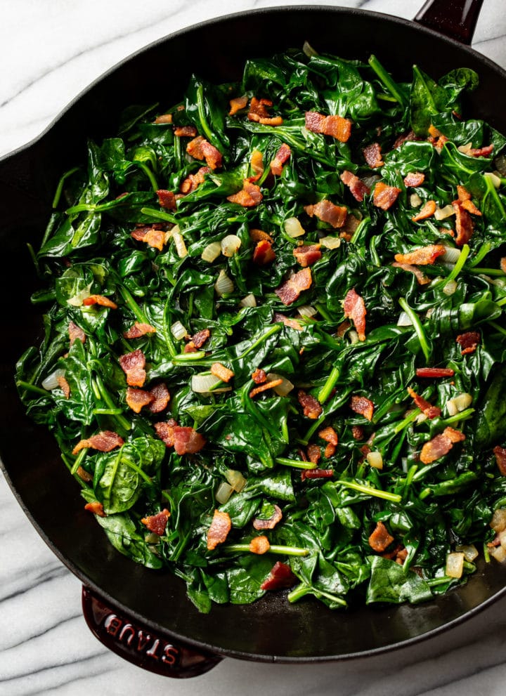 sauteed spinach with bacon in a cast iron skillet