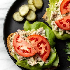 canned mackerel salad on open faced sandwiches with lettuce and tomato on a plate