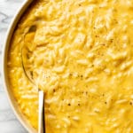 cheesy orzo close-up in a serving bowl with a golden spoon