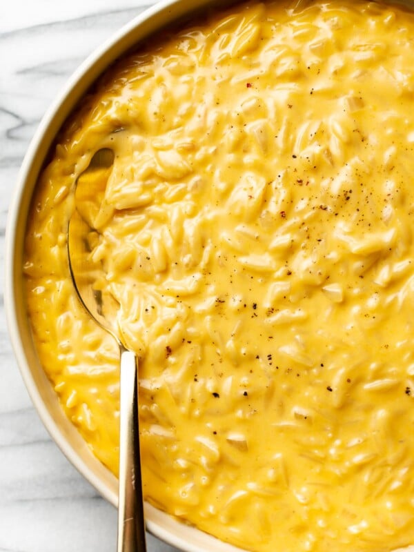 cheesy orzo close-up in a serving bowl with a golden spoon