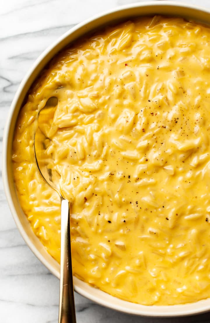 cheesy orzo close-up in a serving bowl with a golden spoon