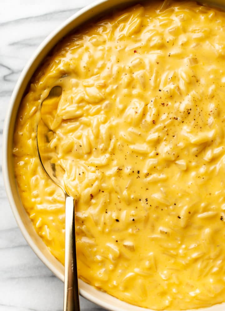cheesy orzo close-up in a serving bowl with a golden spoon