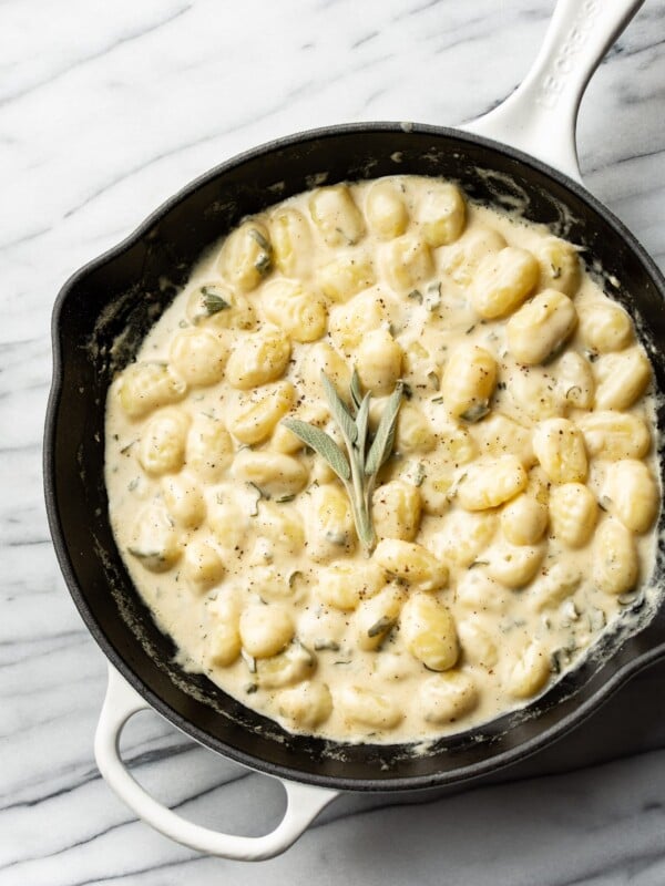 creamy sage gnocchi in a white Le Creuset skillet