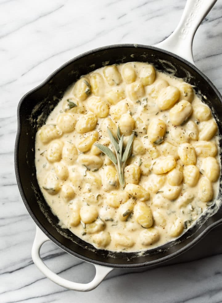 creamy sage gnocchi in a white Le Creuset skillet