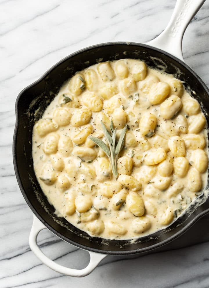 creamy sage gnocchi in a white Le Creuset skillet